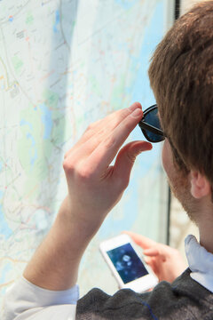 Young blind man at a bus stop using assistive technology to help with map