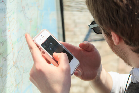 Young blind man at a bus stop using assistive technology to help with map