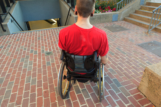 Trendy man with a spinal cord injury in wheelchair planning his access to the subway