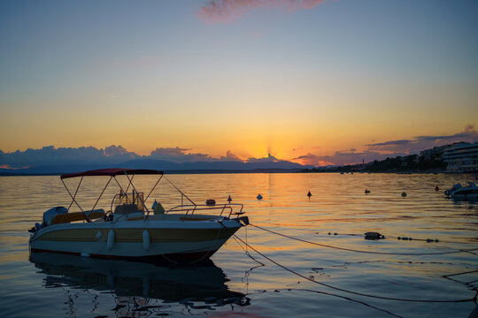 Small motorboat anchored on calm Adriatic waters during a colorful sunset in Crikvenica, Croatia