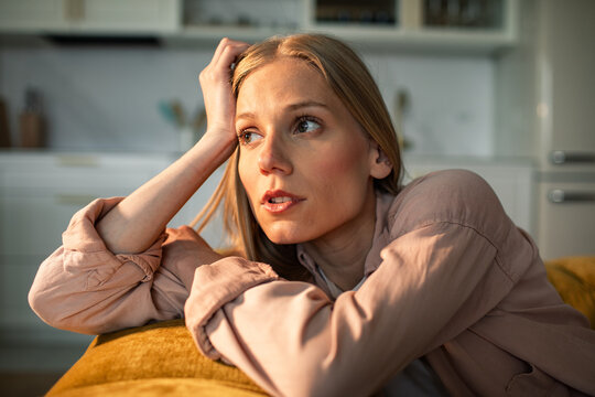 Thoughtful young woman resting on sofa at home