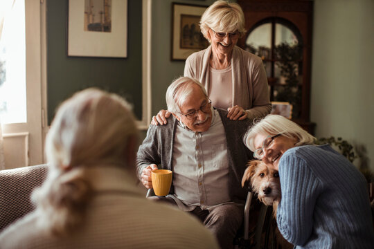 Senior friends sharing coffee with a dog at home