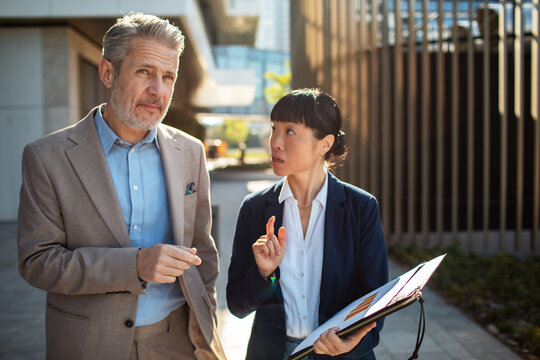Two business colleagues discussing report outside office