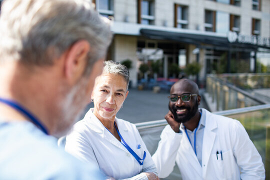 Diverse medical doctors talking outside hospital
