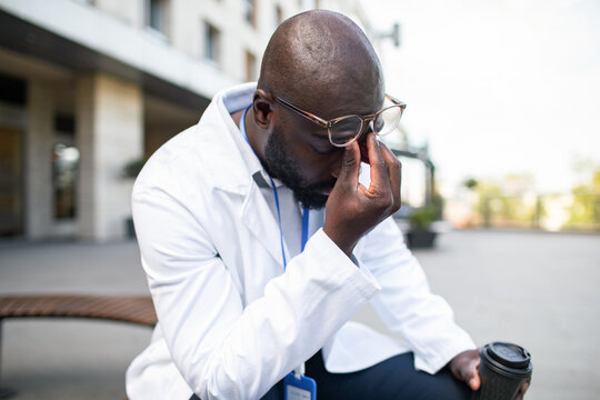 Stressed doctor pinching nose outside hospital