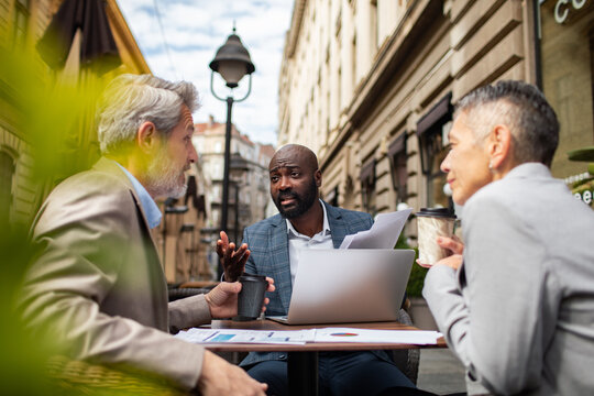 Business colleagues meeting with laptop at outdoor city cafe