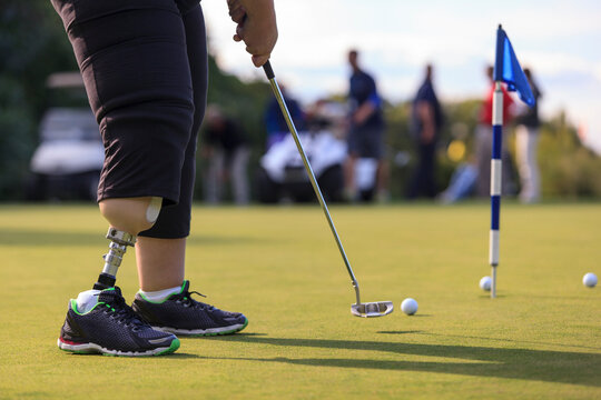 Woman with prosthetic leg at golf putting green