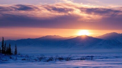 Fototapeta premium Sunrise over snowy mountains in Alaska with orange and purple skies on a cold winter morning
