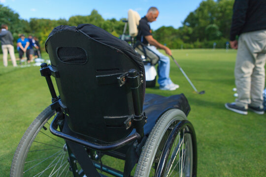 Man with spinal cord injury in an adaptive cart at golf putting green with an instructor
