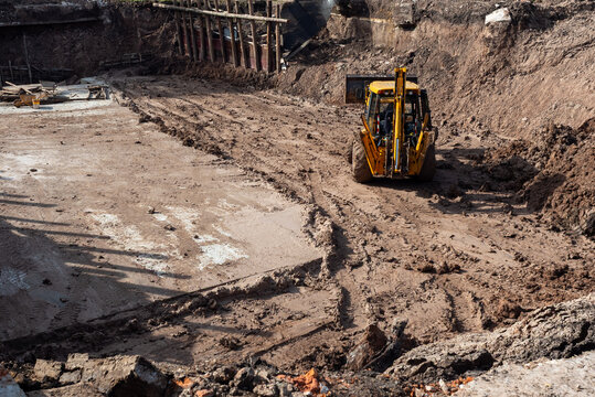Wide shot of a deep construction pit and backhoe loader for building infrastructure.