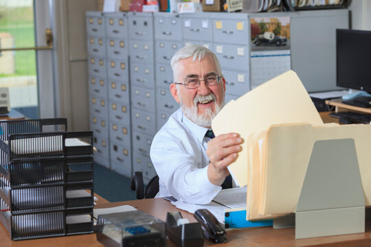 Man with Muscular Dystrophy in a wheelchair filing papers in his office