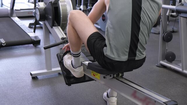 Strong workout session showing rowing machine use in gym with focused technique at early morning