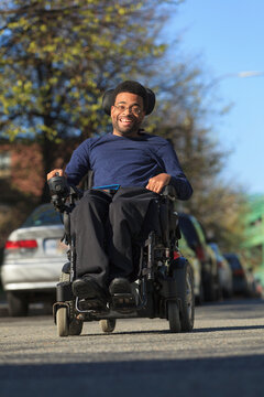 Happy African American man with Cerebral Palsy using his power wheelchair outside