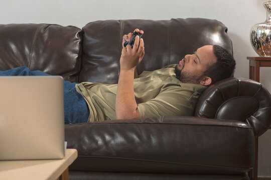 African American man with Down Syndrome using a game controller on couch at home