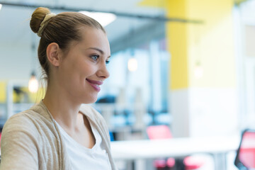 Profile Portrait of Smiling Caucasian Businesswoman with Hair Bun in Office © as-artmedia