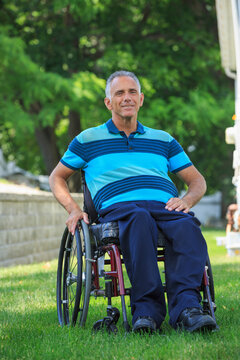 Portrait of happy man with a Spinal Cord Injury in wheelchair on lawn