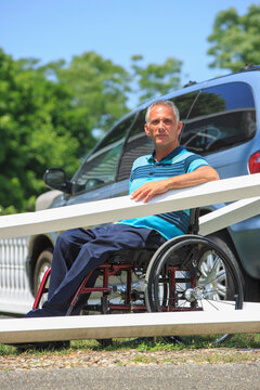 Man with a Spinal Cord Injury in wheelchair in front of his accessible car