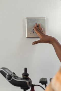 Man with Guillain-Barre Syndrome in his power chair pressing button for elevator