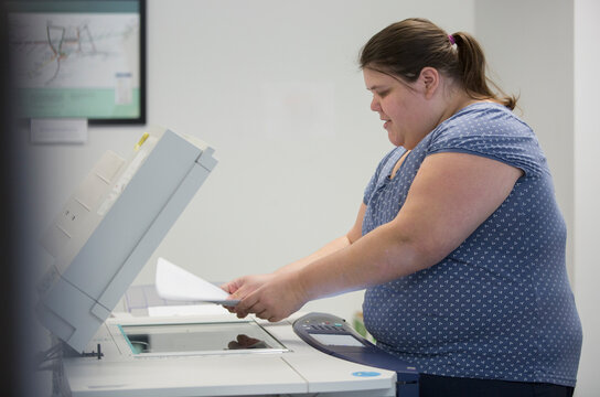Woman with a Learning Disability using a copy machine in office