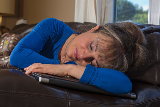 Woman with visual impairment lying down with her computer on sofa in living room