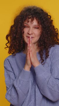 Sneaky cunning curly haired woman with tricky face gesticulating and scheming evil plan, thinking over devious villain idea, cheats, revenge, jokes, pranks. Girl isolated on yellow studio background