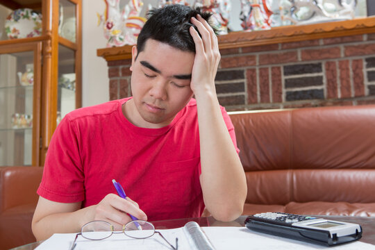 Asian man with Autism working on his homework and getting tired