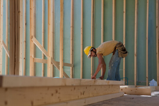 Carpenter placing a stud in a wall frame