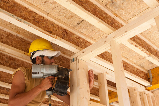 Carpenter using a nail gun on a wall frame