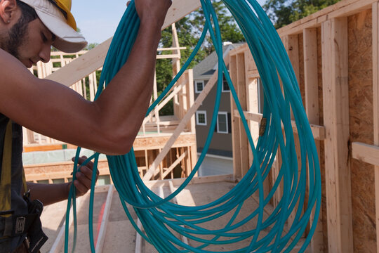 Hispanic carpenter unwinding an air hose at a house under construction