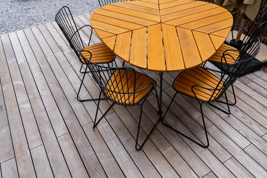Table en bois sur une terrasse en lames de bois, offrant un espace ext&eacute;rieur chaleureux et naturel.