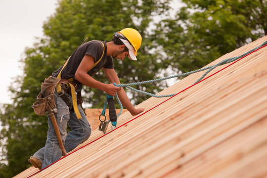 Carpenter using safety strap on the roof of a house under construction