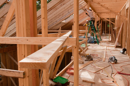 Hispanic carpenters installing window opening on roof at a house under construction