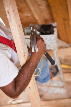 Hispanic carpenter using a hammer at a house under construction