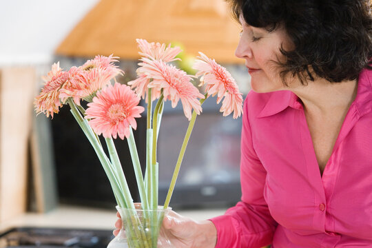 A woman smelling pink daisies