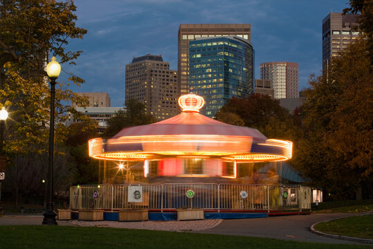 Blurred lights of a carousel spinning at dusk in a city park