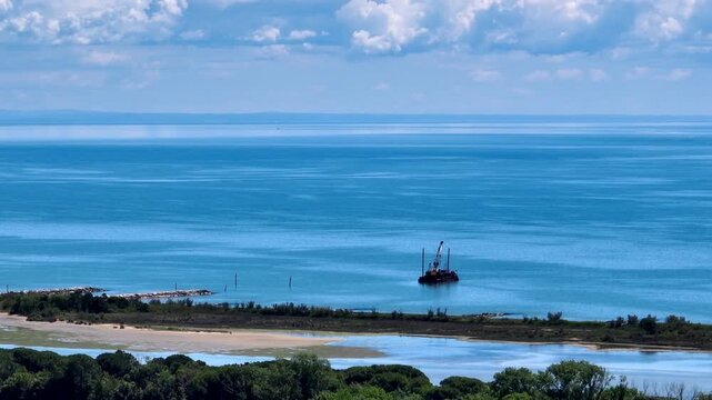 drone panorama over green coastal sand dunes and the open blue Adriatic Sea surface under a clear sky in daylight, near the Piave river mouth, Eraclea, Italy
