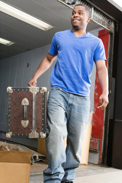 Young man carrying suitcase and smiling