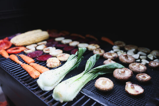 Farm fresh garden vegetables cooking on a pellet grill smoker for a vegetarian dinner. The healthy food is colorful and packed with vitamins and garden nutrients. Delicious!