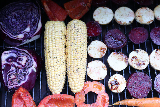 Farm fresh garden vegetables cooking on a pellet grill smoker for a vegetarian dinner. The healthy food is colorful and packed with vitamins and garden nutrients. Delicious!