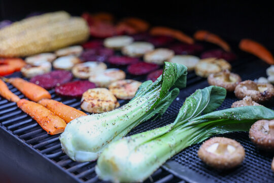 Farm fresh garden vegetables cooking on a pellet grill smoker for a vegetarian dinner. The healthy food is colorful and packed with vitamins and garden nutrients. Delicious!