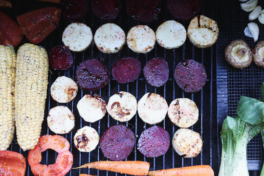 Farm fresh garden vegetables cooking on a pellet grill smoker for a vegetarian dinner. The healthy food is colorful and packed with vitamins and garden nutrients. Delicious!