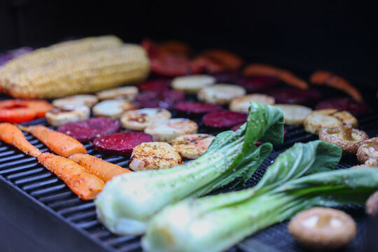 Farm fresh garden vegetables cooking on a pellet grill smoker for a vegetarian dinner. The healthy food is colorful and packed with vitamins and garden nutrients. Delicious!