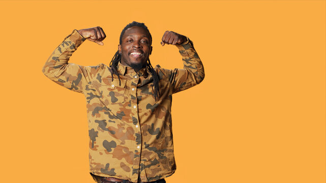 Strong person flexing his muscles on camera and showing his toned physique, athletic man with huge biceps, powerful African American guy feeling confident after going to the gym