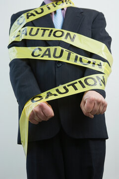 Mid section view of a businessman wrapped in a Caution tape