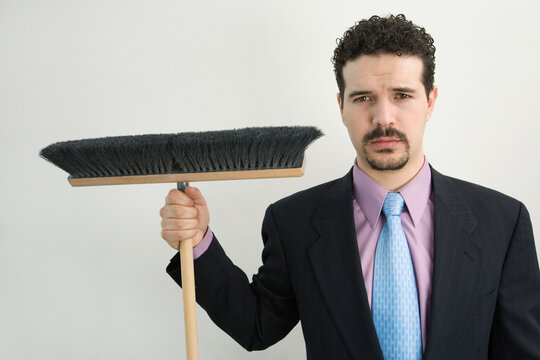 Portrait of a businessman holding a broom