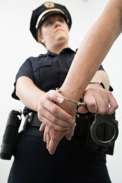 Close up of a person being hand cuffed by a police woman