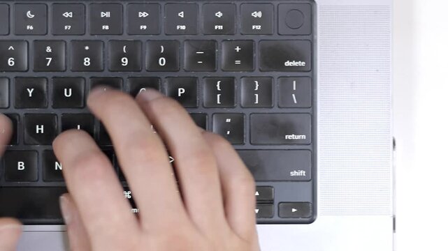Close-up of hands typing on a computer keyboard, end of work