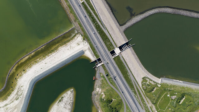 Aerial view of the Vismigratierivier fish migration channel and the Afsluitdijk highway with hydraulic structures and dikes in Kornwerderzand, Friesland, Netherlands.