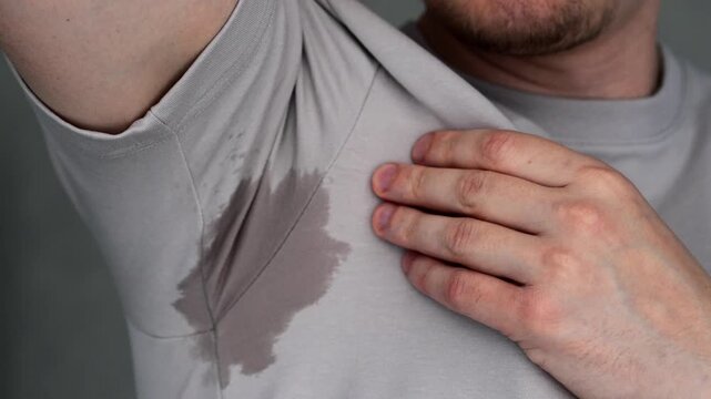 Sweat stains under the arm on a gray T-shirt