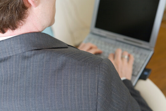Rear view of a business man working on laptop